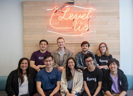 Interns posing with Level Up neon sign